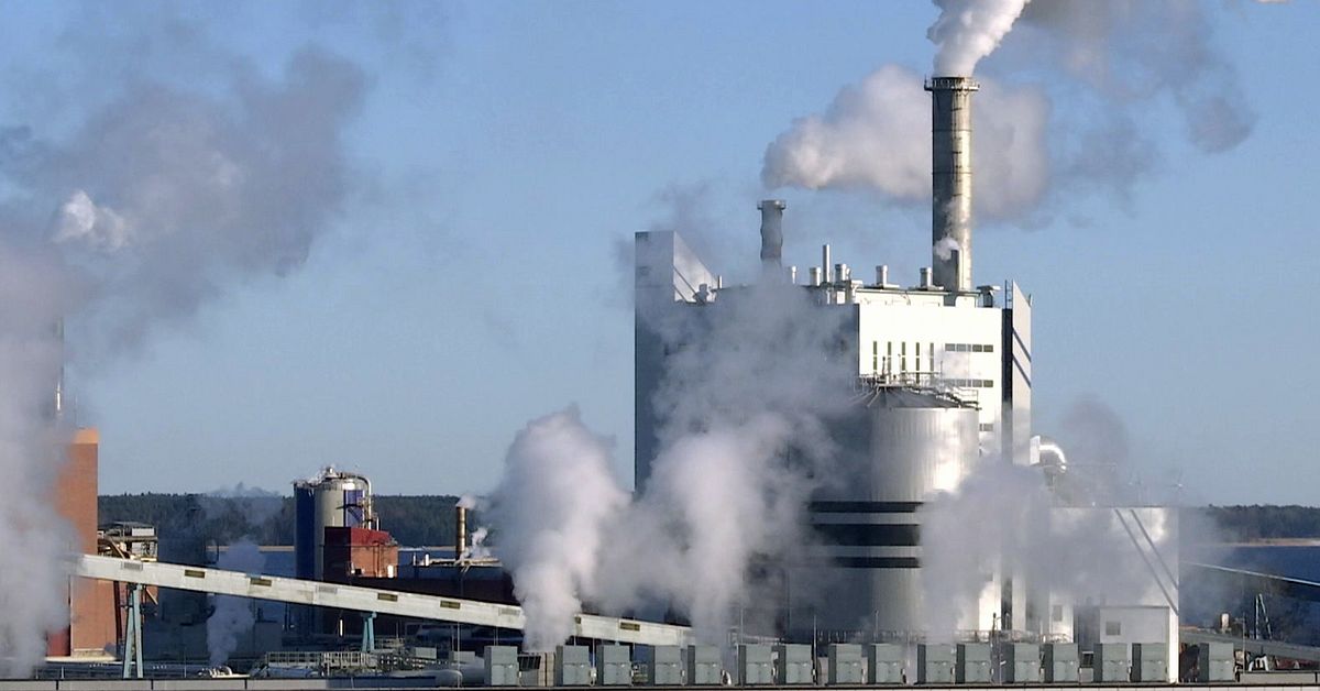 Paper mill industrial complex with multiple smokestacks releasing dense white steam and emissions